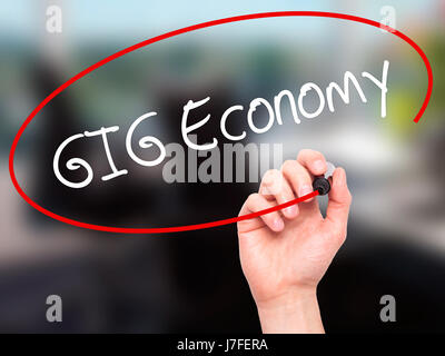 Man mano che scrive GIG economia con il pennarello nero su schermo visivo. Isolato su sfondo. Business, tecnologia internet concetto. Stock Photo Foto Stock