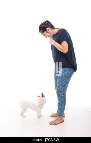 Giovane femmina caucasica giocando con il suo grazioso bichon su sfondo bianco Foto Stock