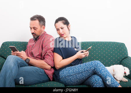 Giovani femmine guardando sopra la sua spalla a ciò che il suo ragazzo è scrivere messaggi sul telefono Foto Stock