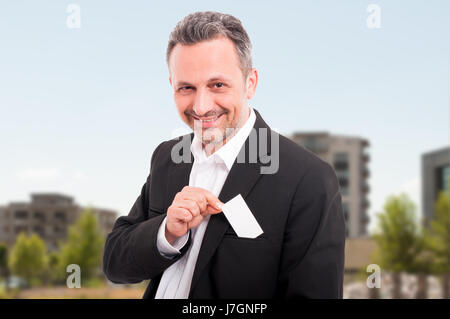 Agente immobiliare di successo prende il business card dalla tasca e sorridente Foto Stock