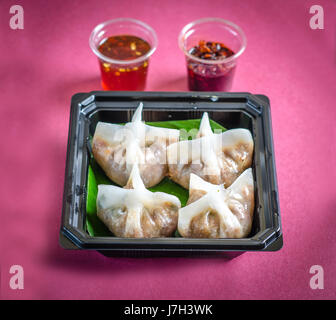 Dim sum con salsa di peperoncino su un sfondo rosa Foto Stock