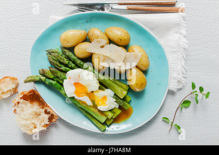 Molla leggera il pranzo sulla piastra. Asparagi Fritti, patate fresche e Uovo affogato con formaggio parmigiano. cibo sano. Foto Stock