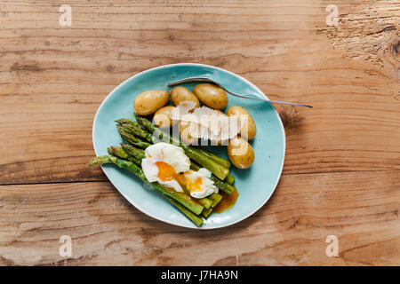 Molla leggera il pranzo sulla piastra. Asparagi Fritti, patate fresche e Uovo affogato con formaggio parmigiano. cibo sano. Foto Stock