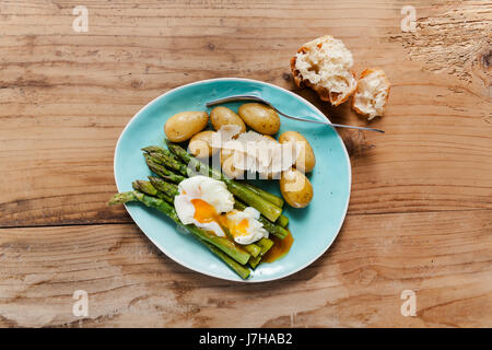 Molla leggera il pranzo sulla piastra. Asparagi Fritti, patate fresche e Uovo affogato con formaggio parmigiano. cibo sano. Foto Stock