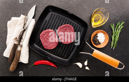 Materie hamburger cotoletta in padella per grigliare. Burger. La cottura di alimenti con posate di taglio per sezionare e spezie Foto Stock