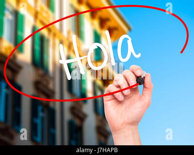 Man mano che scrive Hola (ciao in spagnolo) con pennarello nero su schermo visivo. Isolato su sfondo. Business, tecnologia internet concetto. Stock Ph Foto Stock