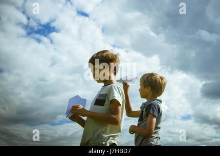 Ragazzi piccoli con piani di carta contro il cielo blu Foto Stock