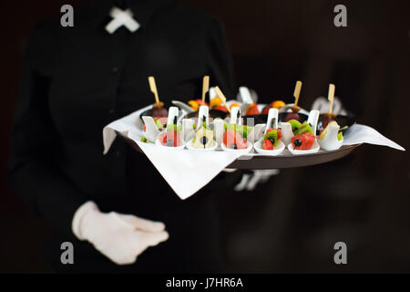 Un cameriere con un vassoio di snack a un banchetto Foto Stock