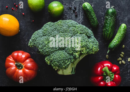 Verdure verdi / verdura fresca on dark ston tabella. Broccoli, pomodoro, calce, pepe, limone, cetriolo sementi e alimenti per il mangiare sano, cottura in Foto Stock