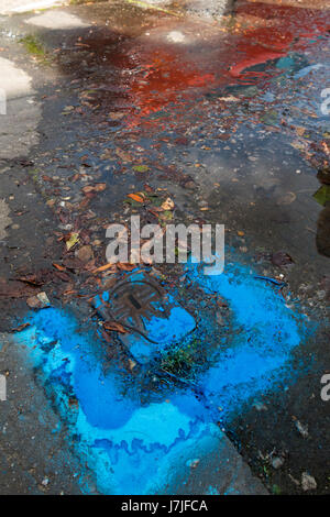 Perdita acqua emergente da una perdita nella Thames Water PLC valvola di arresto contrassegnati da vernice blu nella pavimentazione al di fuori di un ambiente domestico. Twickenham, Regno Unito. Foto Stock