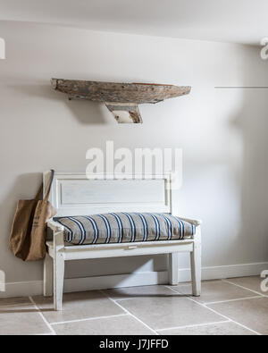 Una barca driftwood sulla parete al di sopra del banco di antiquariato con ticchettio cuscino stripe. Le pareti sono dipinte in Farrow & Ball forte emulsione bianca e il banco ho Foto Stock