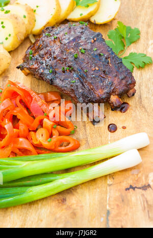 Grigliata di carne di maiale alla brace bimbo indietro nervature servito con patate e sottaceti Foto Stock