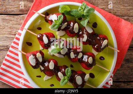 Estate fragole dessert con cioccolato, menta e mandorle close-up su una piastra orizzontale di vista da sopra Foto Stock