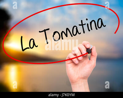 Man mano che scrive La Tomatina con pennarello nero su schermo visivo. Isolato sulla natura. Business, tecnologia internet concetto. Foto Stock