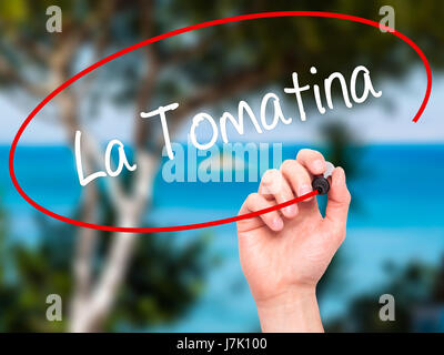 Man mano che scrive La Tomatina con pennarello nero su schermo visivo. Isolato sulla natura. Business, tecnologia internet concetto. Foto Stock
