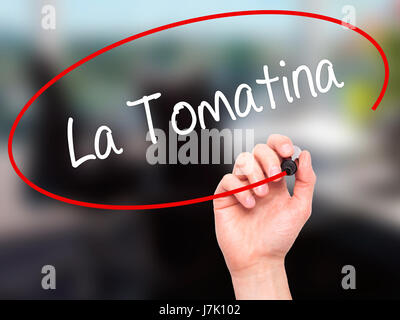 Man mano che scrive La Tomatina con pennarello nero su schermo visivo. Isolato su office. Business, tecnologia internet concetto. Foto Stock