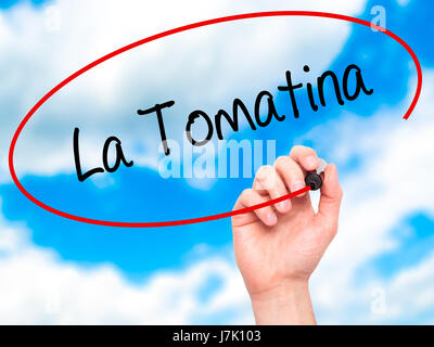 Man mano che scrive La Tomatina con pennarello nero su schermo visivo. Isolato su sky. Business, tecnologia internet concetto. Foto Stock