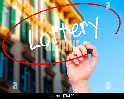 Man mano che scrive lotteria con pennarello nero su schermo visivo. Isolato sulla città. Business, tecnologia internet concetto. Stock Photo Foto Stock