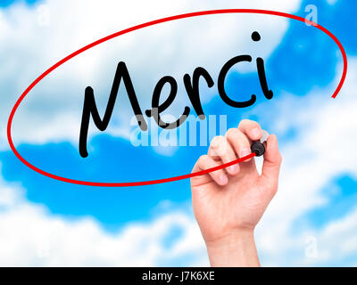 Man mano che scrive Merci (grazie in francese) con pennarello nero su schermo visivo. Isolato su sfondo. Business, tecnologia internet concetto. Stoc Foto Stock