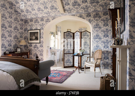 Grande camera da letto con stanza da bagno annessa con toile de jouy wallpaper e corrispondente schermata di piegatura. Foto Stock