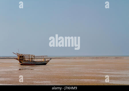 Sambuco tradizionale barca ormeggiata lungo la costa durante la bassa marea nel villaggio Al-Ruwais, Qatar, Medio Oriente. Foto Stock