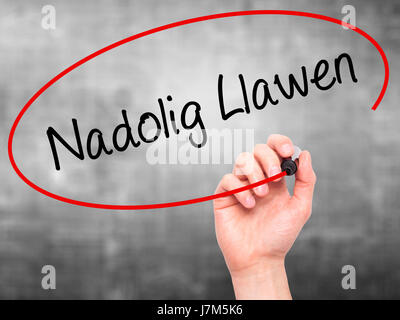 Man mano che scrive Nadolig Llawen (Buon Natale in lingua gallese) con pennarello nero su schermo visivo. Isolato su sfondo. Business, tecnologia internet Foto Stock