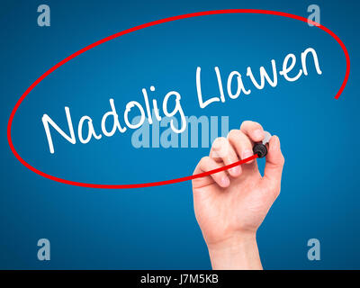 Man mano che scrive Nadolig Llawen (Buon Natale in lingua gallese) con pennarello nero su schermo visivo. Isolato su sfondo. Business, tecnologia internet Foto Stock