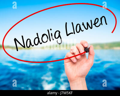 Man mano che scrive Nadolig Llawen (Buon Natale in lingua gallese) con pennarello nero su schermo visivo. Isolato su sfondo. Business, tecnologia internet Foto Stock