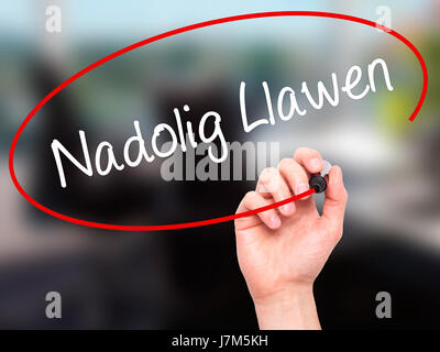 Man mano che scrive Nadolig Llawen (Buon Natale in lingua gallese) con pennarello nero su schermo visivo. Isolato su sfondo. Business, tecnologia internet Foto Stock