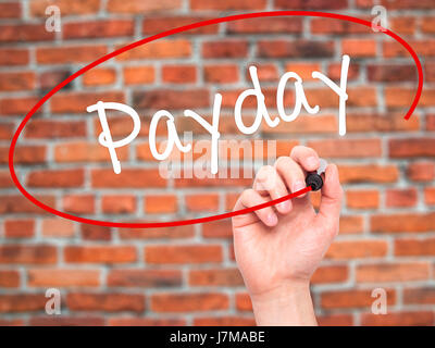 Man mano che scrive Payday con pennarello nero su schermo visivo. Isolato su mattoni. Business, tecnologia internet concetto. Stock Photo Foto Stock