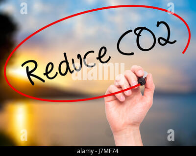 Man mano che scrive di ridurre le emissioni di CO2 con pennarello nero su schermo visivo. Isolato su sfondo. Business, tecnologia internet concetto. Stock Photo Foto Stock