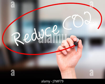 Man mano che scrive di ridurre le emissioni di CO2 con pennarello nero su schermo visivo. Isolato su sfondo. Business, tecnologia internet concetto. Stock Photo Foto Stock