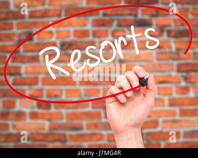 Man mano che scrive Resorts con pennarello nero su schermo visivo. Isolato su sfondo. Business, tecnologia internet concetto. Stock Photo Foto Stock