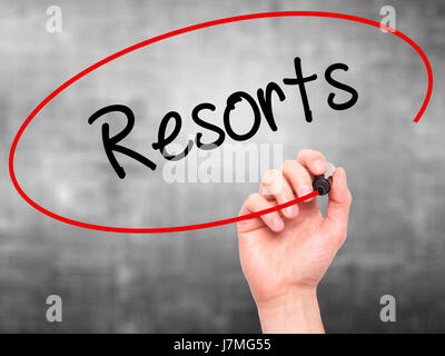 Man mano che scrive Resorts con pennarello nero su schermo visivo. Isolato su sfondo. Business, tecnologia internet concetto. Stock Photo Foto Stock