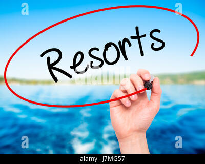 Man mano che scrive Resorts con pennarello nero su schermo visivo. Isolato su sfondo. Business, tecnologia internet concetto. Stock Photo Foto Stock