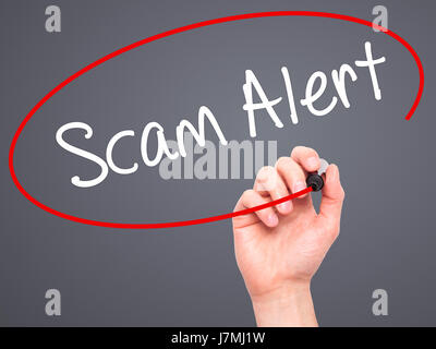 Man mano che scrive Scam Alert con pennarello nero su schermo visivo. Isolato su grigio. Business, tecnologia internet concetto. Stock Photo Foto Stock