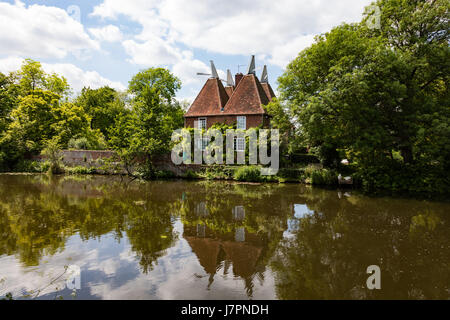 Un grazioso oast house si riflette nel fiume Medway vicino Yalding, Kent, Regno Unito. Foto Stock