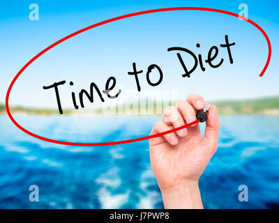 Man mano che scrive il tempo di dieta con pennarello nero su schermo visivo. Isolato sulla natura. Business, tecnologia internet concetto. Foto Stock