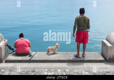 Paio di pesca sul dockside in Spagna. Cane in centro. Foto Stock