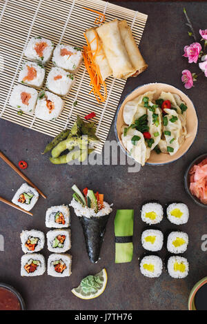 Vari sushi, pranzo Giapponese e contorni e salse di immersione su sfondo scuro. Vista dall'alto, uno spazio vuoto Foto Stock