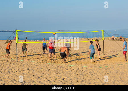 Le persone aventi divertirsi giocando a pallavolo in spiaggia a banchi di sabbia spiaggia, Poole, Dorset nel Maggio Foto Stock