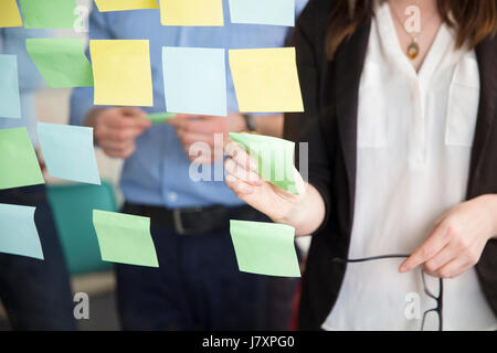 Sezione mediana di imprenditrice Sticking Nota Mentre in piedi da Executive Foto Stock