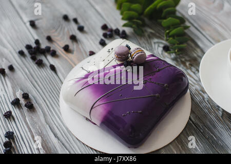 Viola tradizionale torta di frutti di bosco e macaron souffle dessert e mandorla dacquoise, confit di lampone, strato croccante con nocciole caramellate e polvere di lampone, mousse sulla base di cioccolata amara servita su un tavolo di legno dello sfondo. In stile rustico e luce naturale. Vista dall'alto. Foto Stock