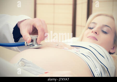 Medico utilizzando uno stetoscopio esaminando la donna incinta gravidanza medico Donna salute concetto Foto Stock