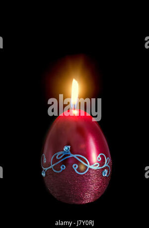 Forma di uovo, ovale cero pasquale, fiamma, isolata, vicino, sfondo scuro. Foto Stock