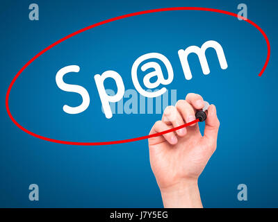 Man mano che scrive lo spam con pennarello nero su schermo visivo. Isolato su blu. Business, tecnologia internet concetto. Immagine di stock Foto Stock