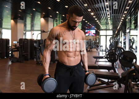 Atleta che lavora fuori bicipite in una palestra - Dumbbell riccioli di concentrazione Foto Stock