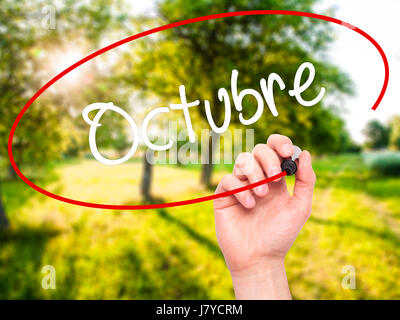 Man mano che scrive "Octubre" (In Spagnolo: ottobre) con pennarello nero su schermo visivo. Isolato sulla natura. Business, tecnologia internet conc Foto Stock