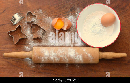 Legno di rotolamento con cottura ingredienti, farina, uova, cookie cutters sul pannello di legno Foto Stock