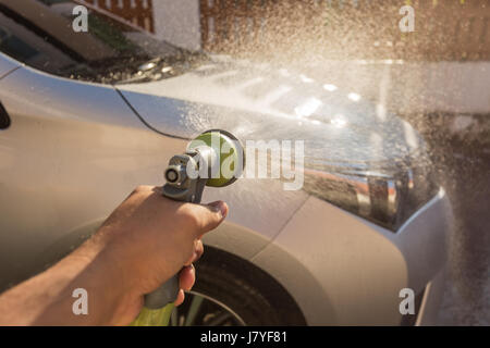 Chiudere la mano la spruzzatura di acqua di lavaggio auto. Auto privata e lavaggio. Focus sulla pistola a spruzzo Foto Stock